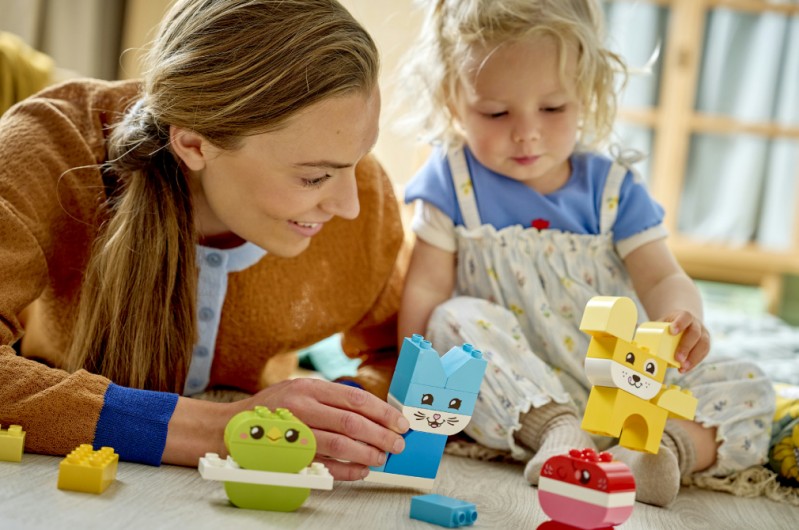 Family playing with LEGO building toys creating colourful structures.